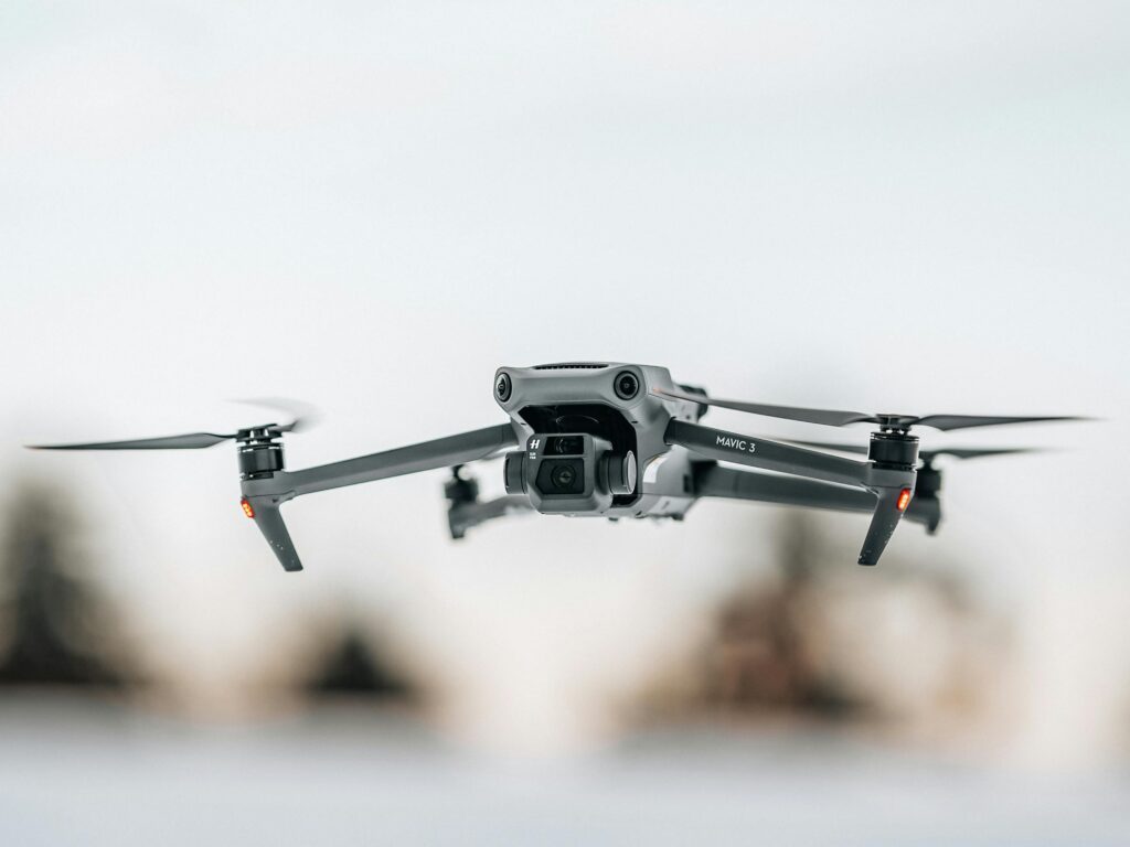 Close-up of a drone flying mid-air with propellers spinning against a clear sky.
