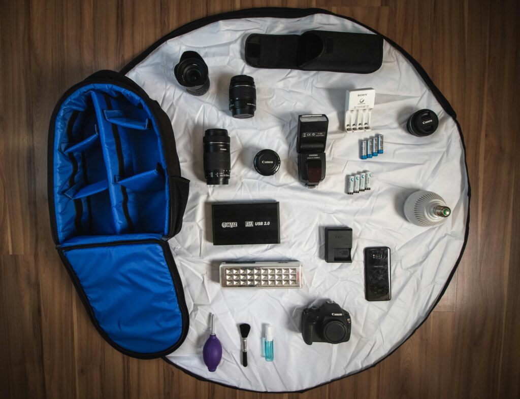 Flat lay of diverse photography tools including lenses, Canon camera, and accessories.