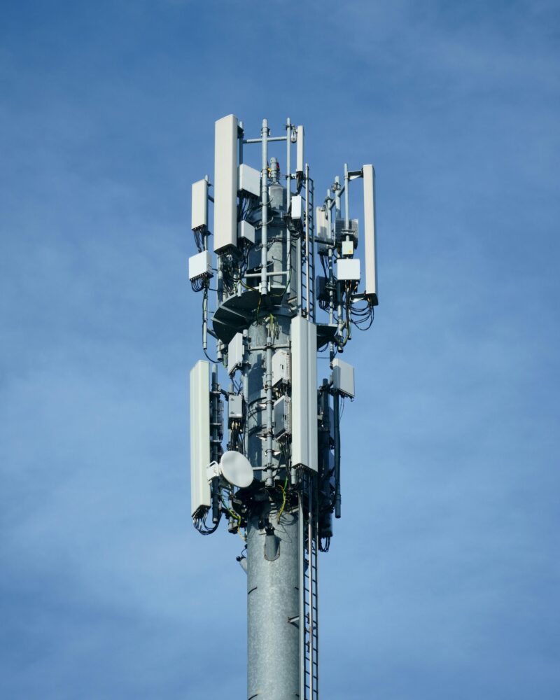 Telecommunication transmission tower with multiple antennas against a clear blue sky, showcasing modern connectivity technology.