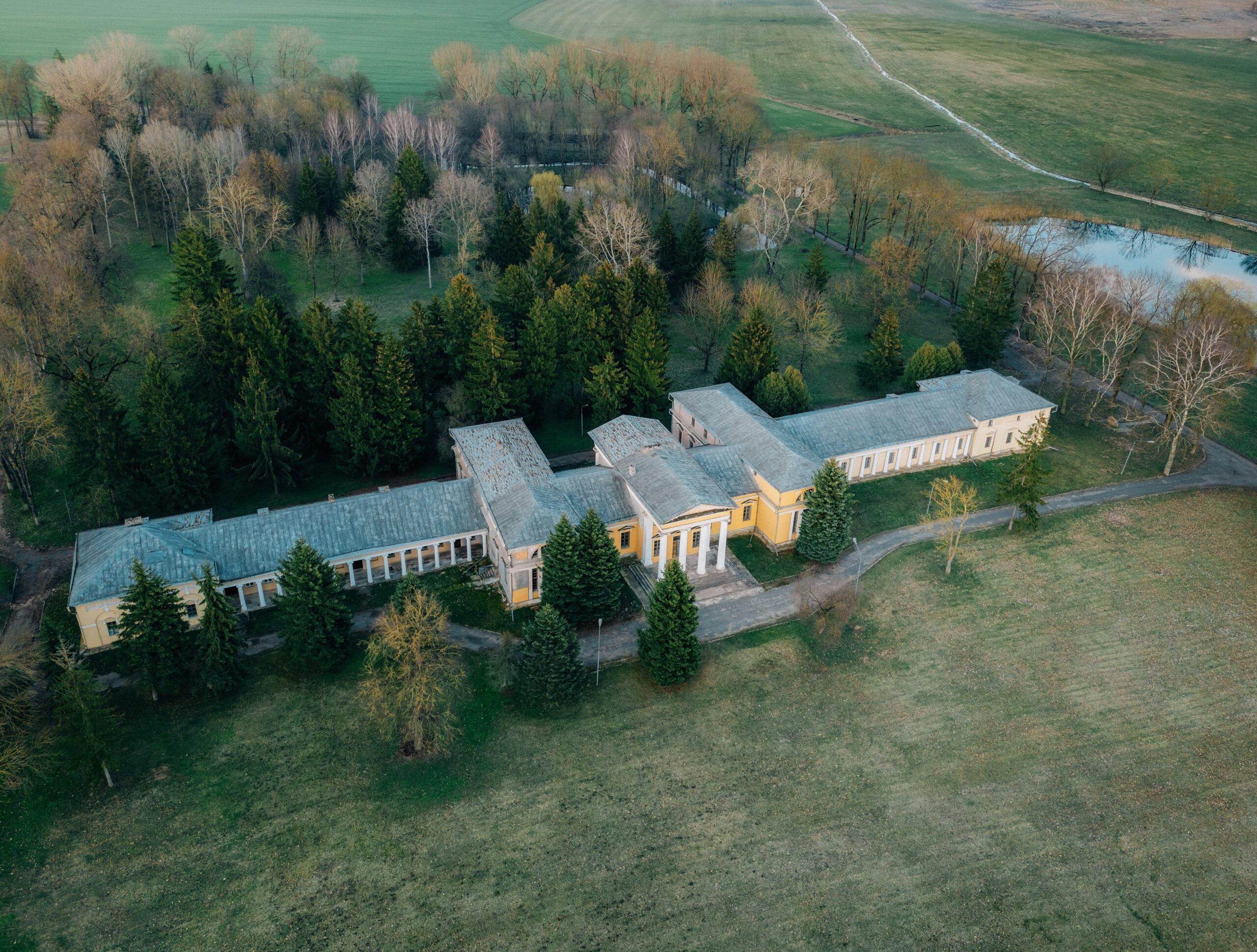 Drone shot of Rdułtowski Palace surrounded by lush countryside and forest in Snoŭ, Belarus.